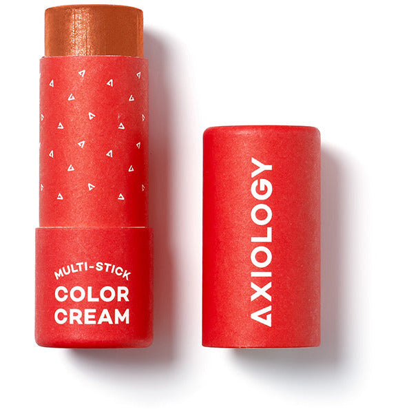 A tube of axilogy multi-stick color cream with its cap removed, displaying the product against a white background.