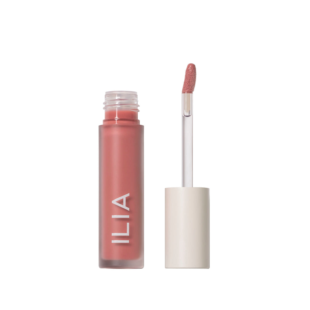 A tube of ilia brand lip gloss with an open cap and applicator wand displayed beside it.