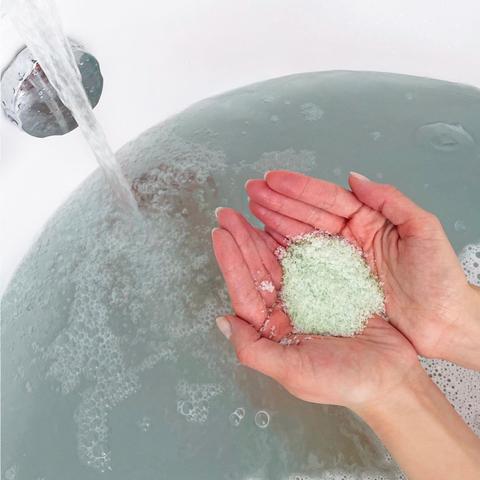 Adding bath salts to a tub of water.