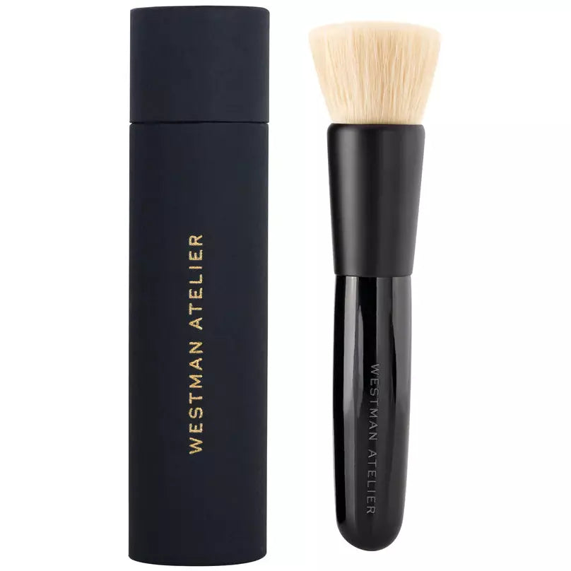 Makeup foundation stick with its accompanying application brush.