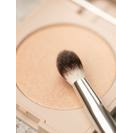 Makeup brush resting on a compact powder.