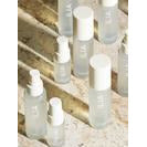 A collection of translucent skincare bottles on a concrete surface.