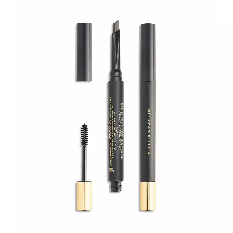 A set of three cosmetic items, including mascara, eyebrow pencil, and eyeliner, with black and gold packaging, aligned on a white background.