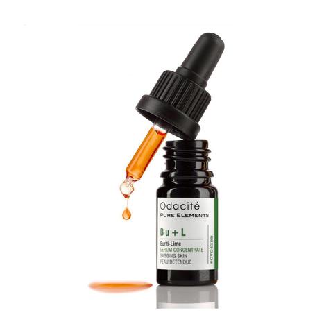 Dropper bottle of odacite facial serum with a single drop suspended from the pipette, isolated on a white background.