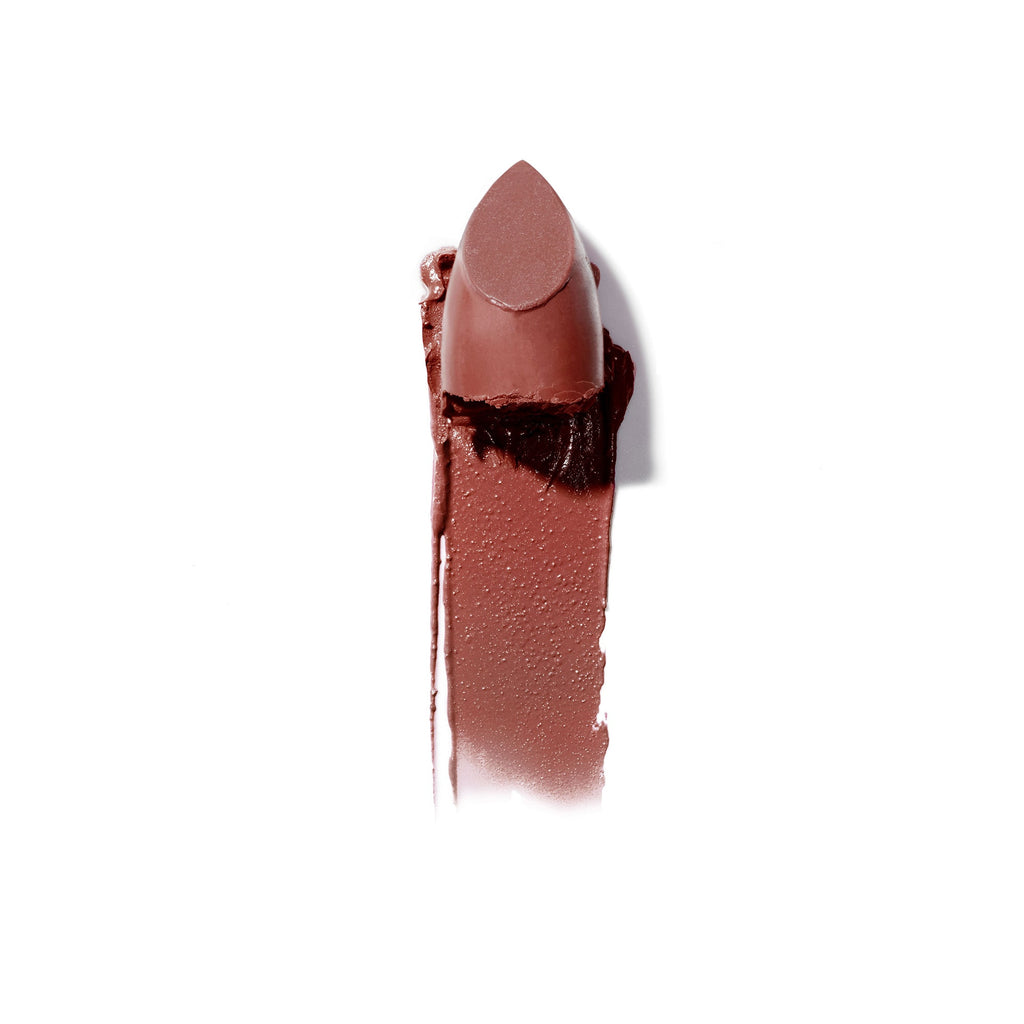 A single lipstick with a broken tip lying next to a swatch of its color on a white background.