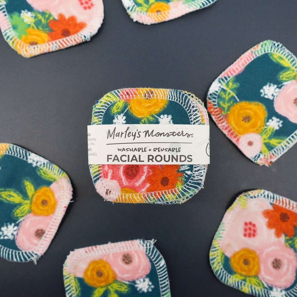 A pack of marley's monsters washable and reusable facial rounds with floral patterns on a gray surface.