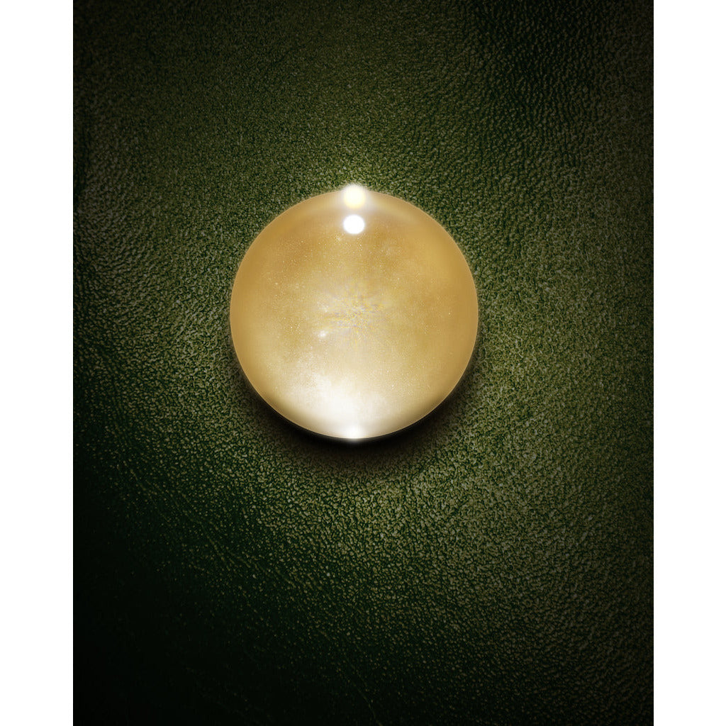 A solitary pearl atop a textured green surface, illuminated from above.