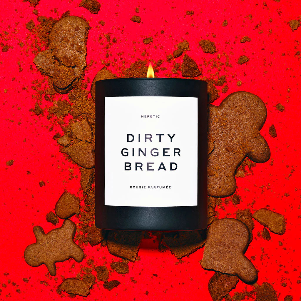 Scented candle labeled "dirty ginger bread" surrounded by gingerbread cookies on a red background.