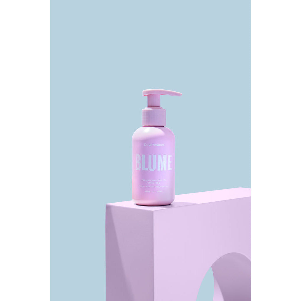 A pump bottle of blume skincare product displayed on a matching color block against a pastel backdrop.