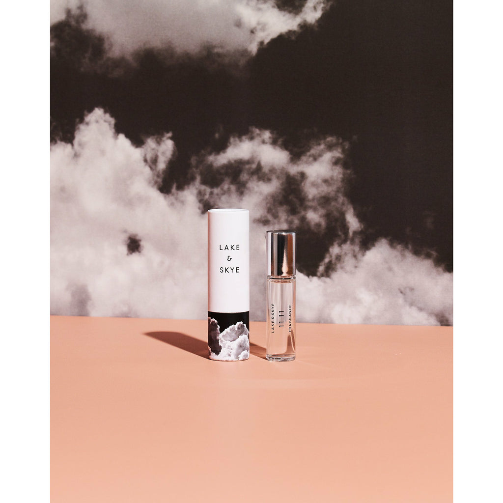 Two skincare products with minimalist design on a peach surface against a cloudy backdrop.