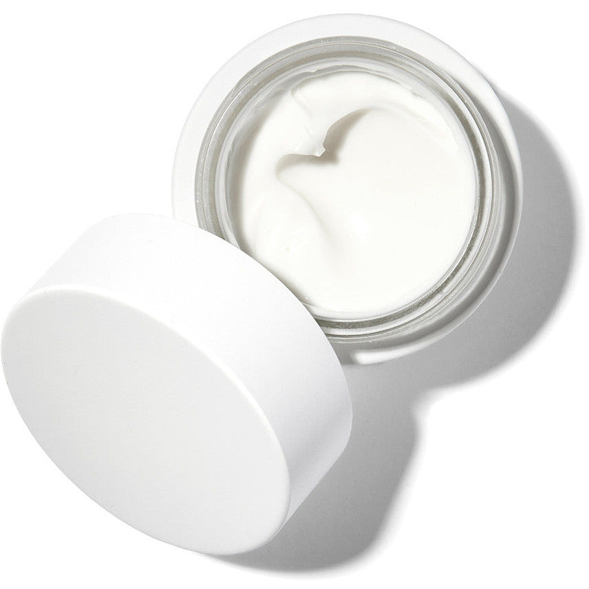 Open jar of cream with a textured surface, casting a shadow on a white background.