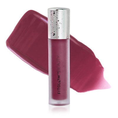 A tube of fitglow beauty lip gloss lying next to a swatch of its pink shade on a white background.