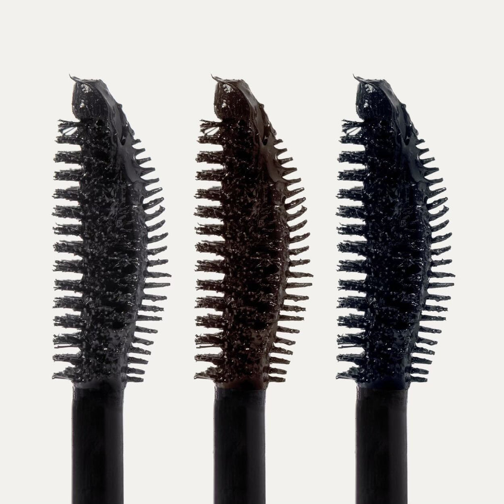 Three mascara wands with varying amounts of product on the bristles.