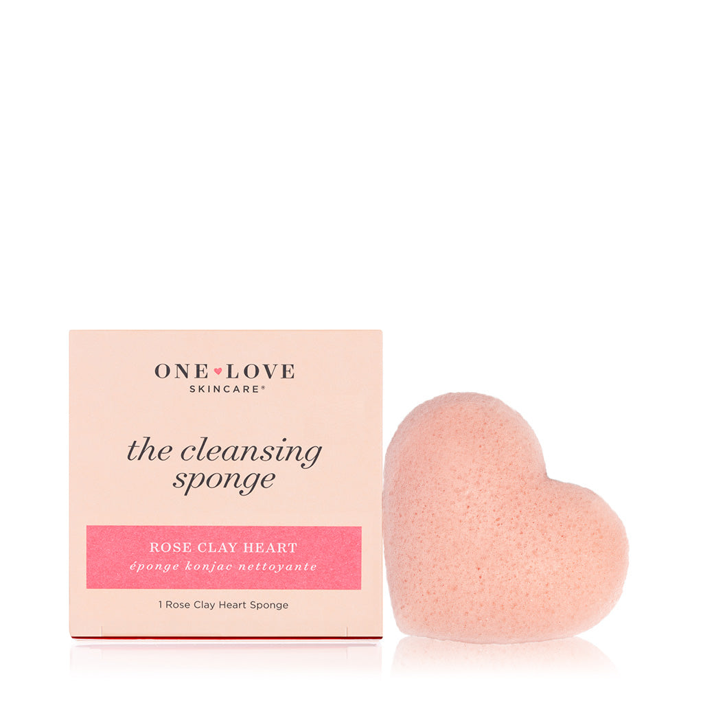 A pink heart-shaped facial cleansing sponge next to its packaging.