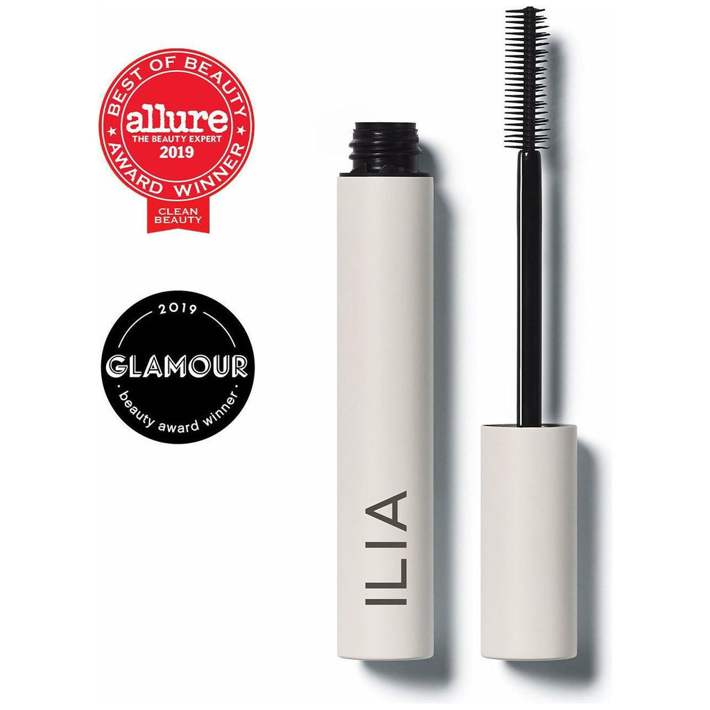 A tube of ilia brand mascara with its brush displayed to the side, along with seals indicating "allure best of beauty 2019 expert" and "glamour 2019 beauty award.
