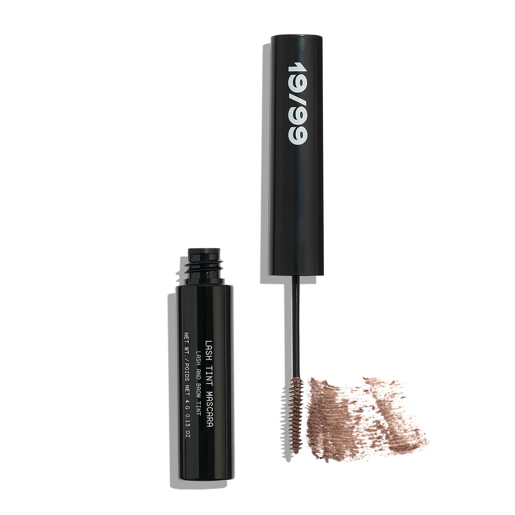 Tube of mascara with brush applicator and product smudge on white background.