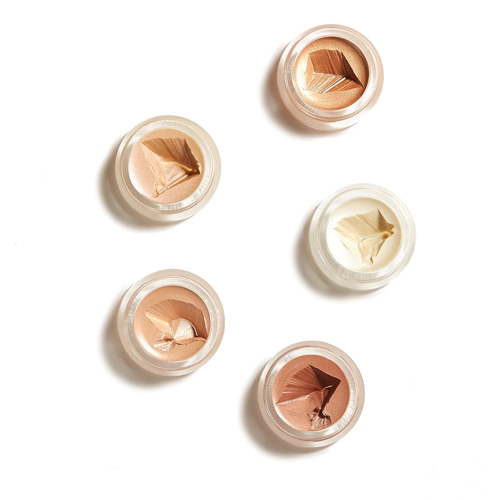 Five jars of cosmetic cream with various shades, some with visible texture marks, displayed on a white surface.