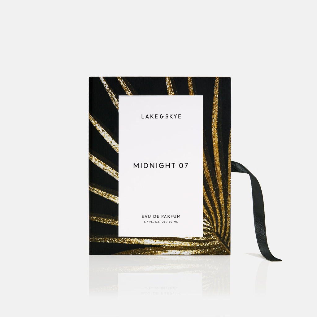 A bottle of lake & skye midnight 07 eau de parfum with a black and gold design and a ribbon on a white background.