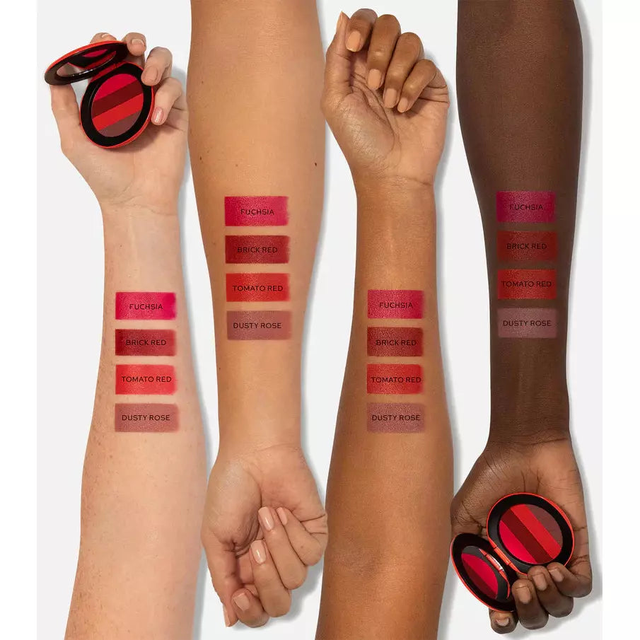 Swatches of red lipstick shades displayed on arms of varying skin tones.
