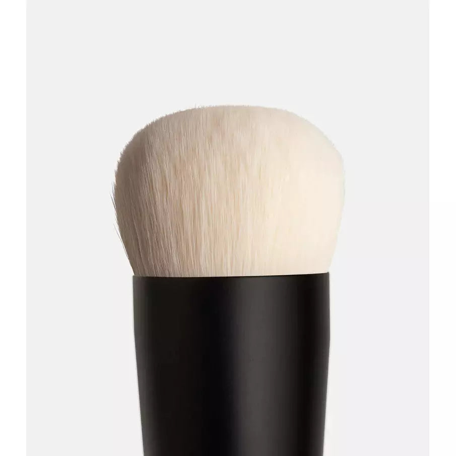 Close-up of a makeup brush with a black handle against a neutral background.