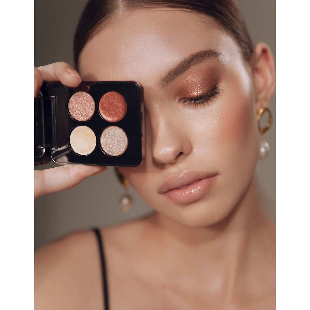 A person showcasing an eyeshadow palette while displaying their makeup that possibly uses the same shades.