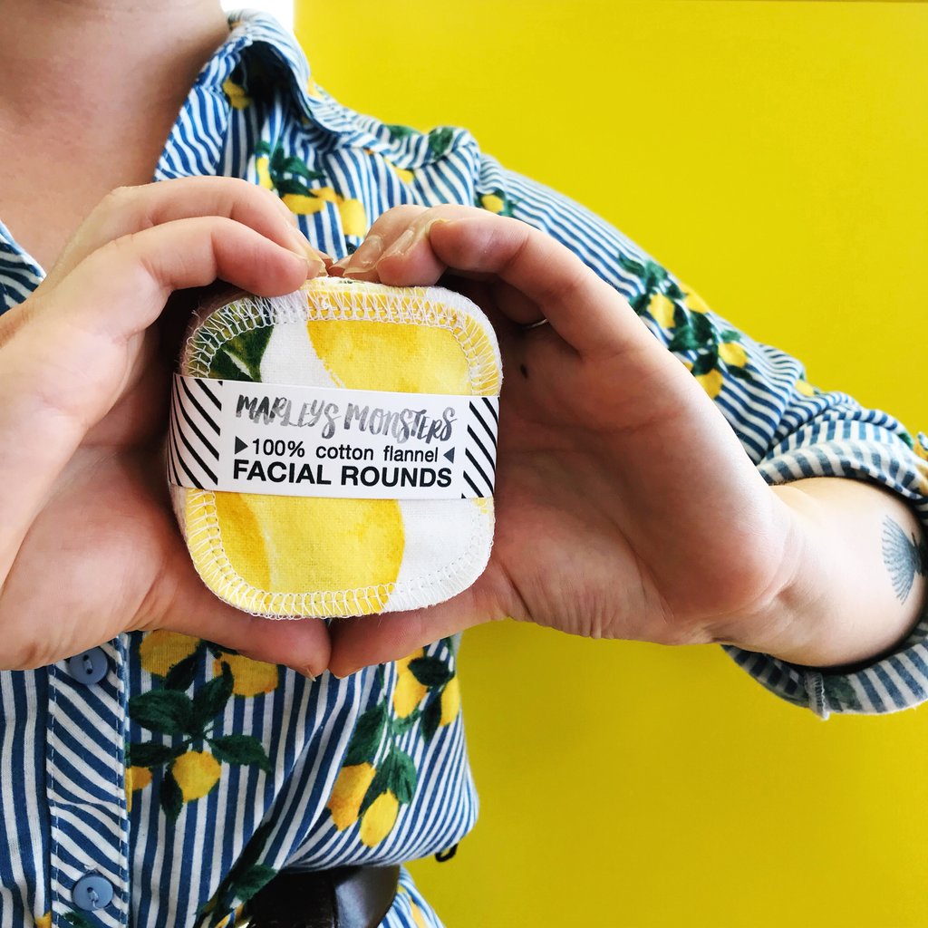 Person holding a reusable cotton facial round against a yellow background.