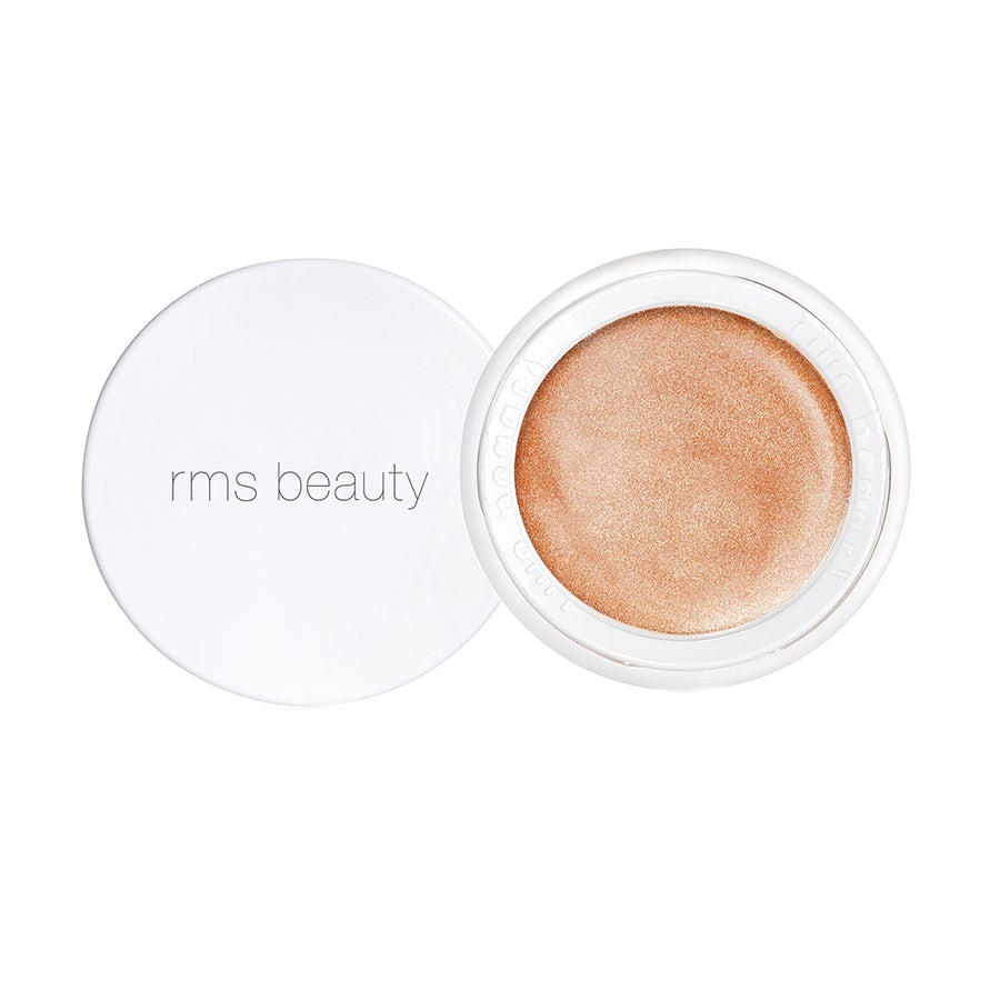 Open container of rms beauty highlighter with the lid to the side, isolated on a white background.