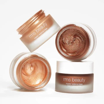 Two jars of rms beauty highlighter cream in different shades, one open with the product visible.