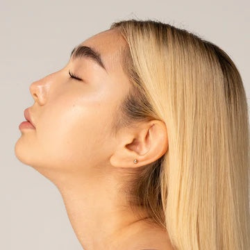 Profile view of a woman with blonde hair and closed eyes against a neutral background.
