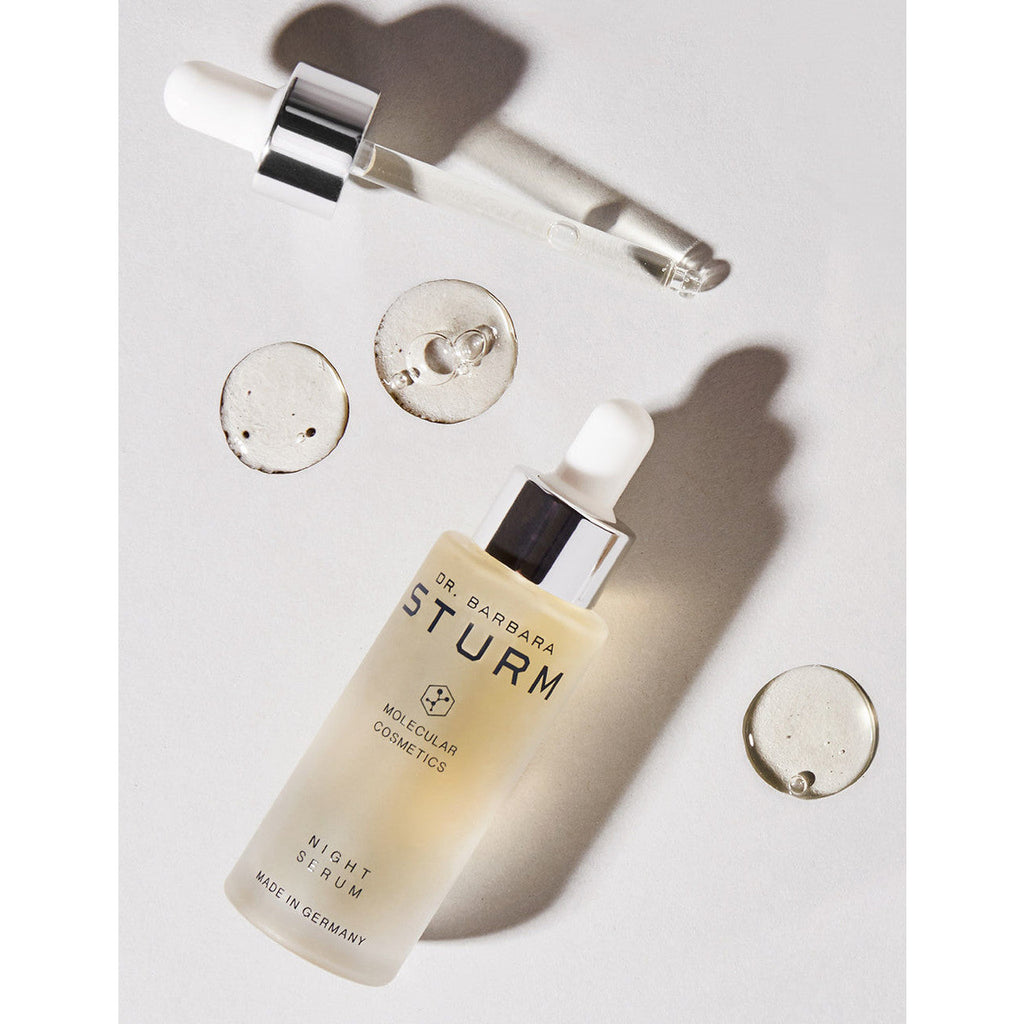 A skincare serum bottle with a dropper and small liquid samples on a clean, well-lit surface.
