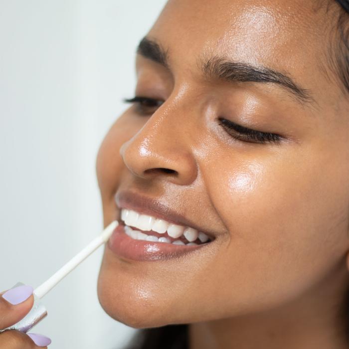 Woman applying clear lip gloss.