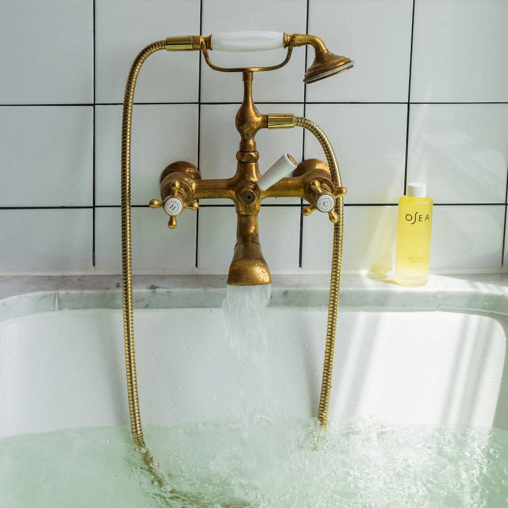 Vintage brass bathtub faucet with running water and bubbles.