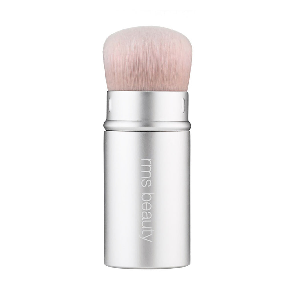 A makeup kabuki brush from rms beauty with a silver handle.