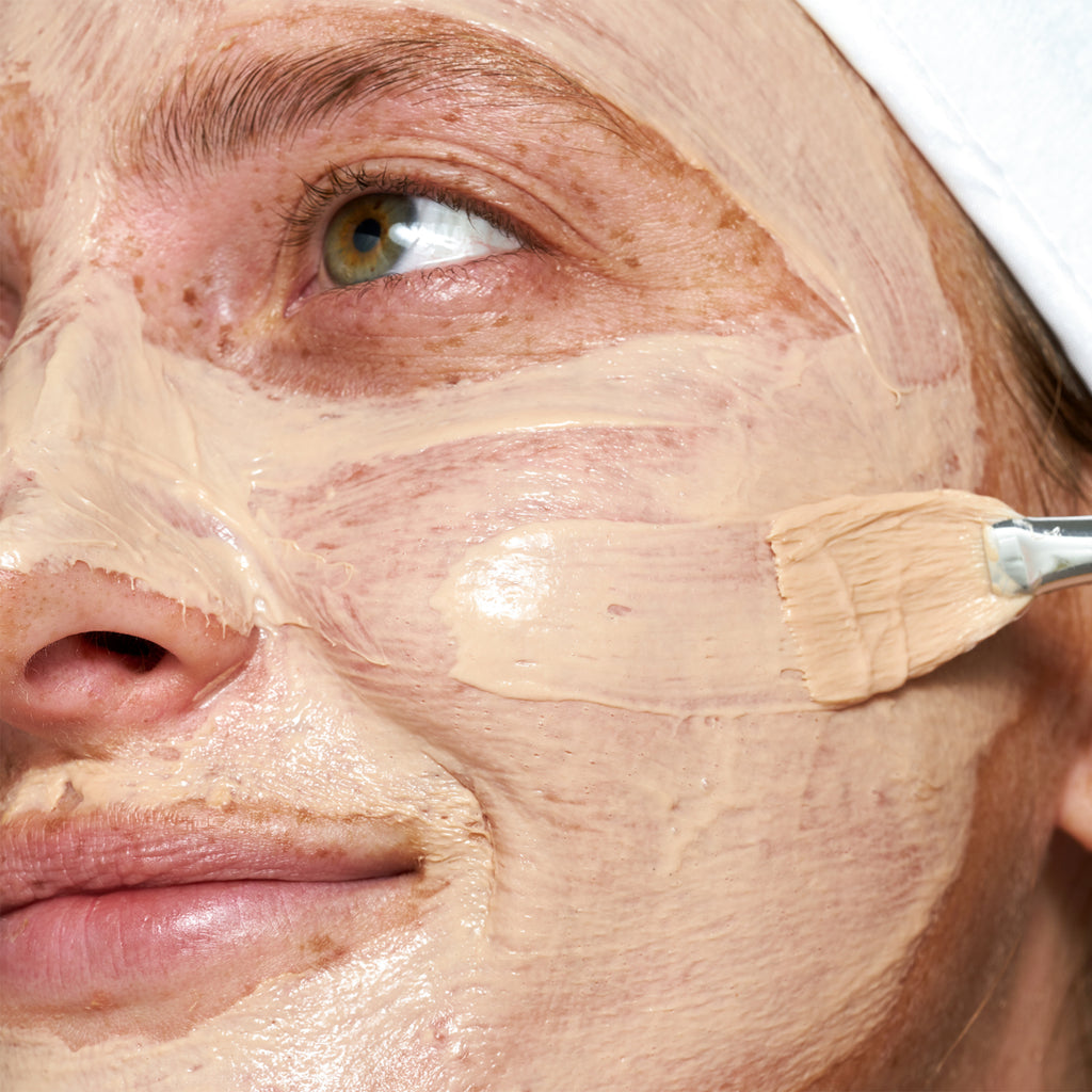 Close-up of a person having a facial mask applied with a brush.