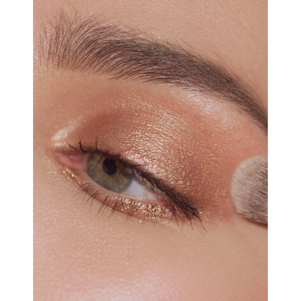 Close-up of an eye with glittery eyeshadow and natural, full eyebrows.