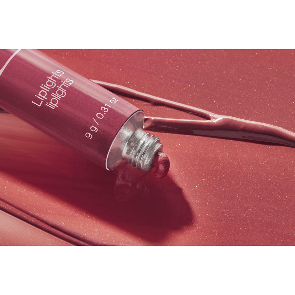 A tube of liquid lipstick with its contents spilling out onto a glossy surface.