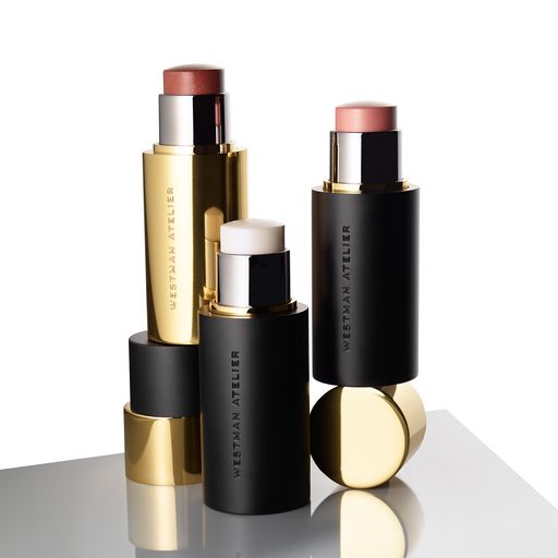 A collection of luxury lipstick tubes with caps off, showing various shades and a balm.