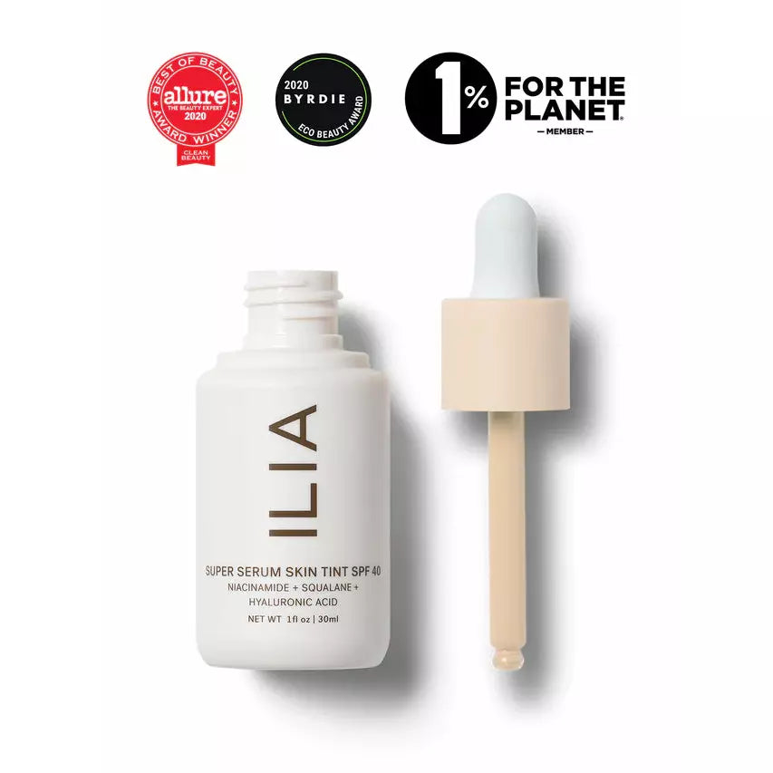 A cosmetic dropper bottle labeled "ilia super serum skin tint spf 40" alongside badges indicating beauty awards and environmental commitment.