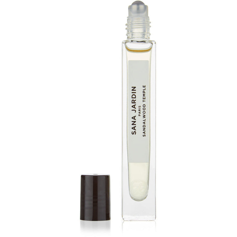 Clear glass rollerball perfume bottle with black cap displaying the label "sana jardin sandalwood temple".