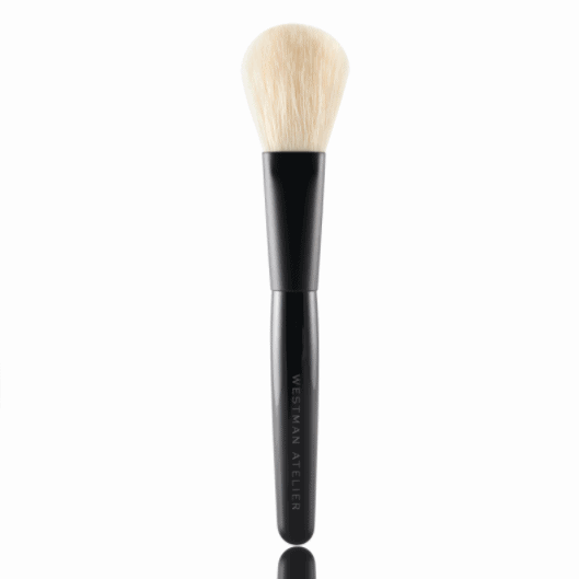 Makeup brush with black handle reflected on a surface.