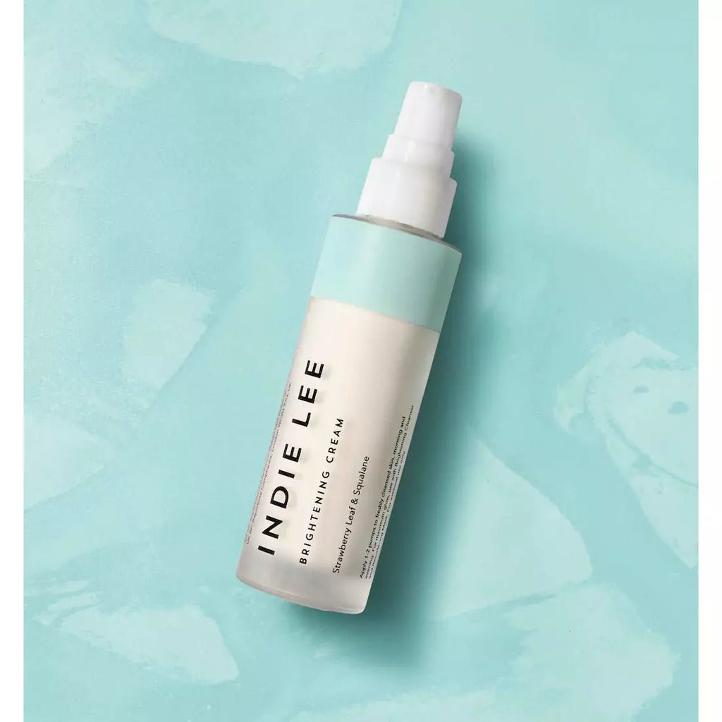 Bottle of indie lee skincare product on a pastel blue background.
