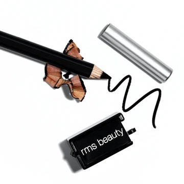 An eyeliner pencil with shavings next to its cap and a cosmetic sharpener on a white surface.