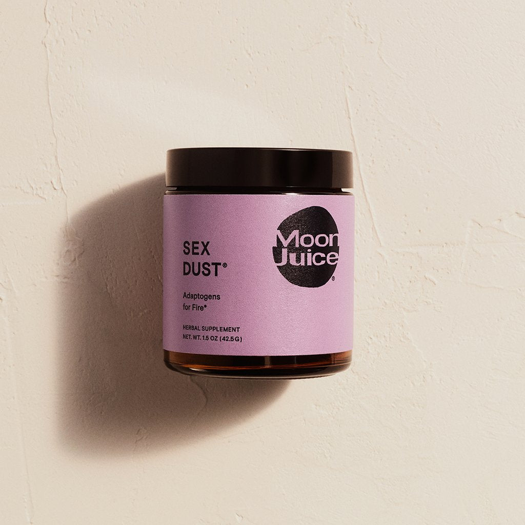 A jar of "sex dust" herbal supplement by moon juice against a textured background.