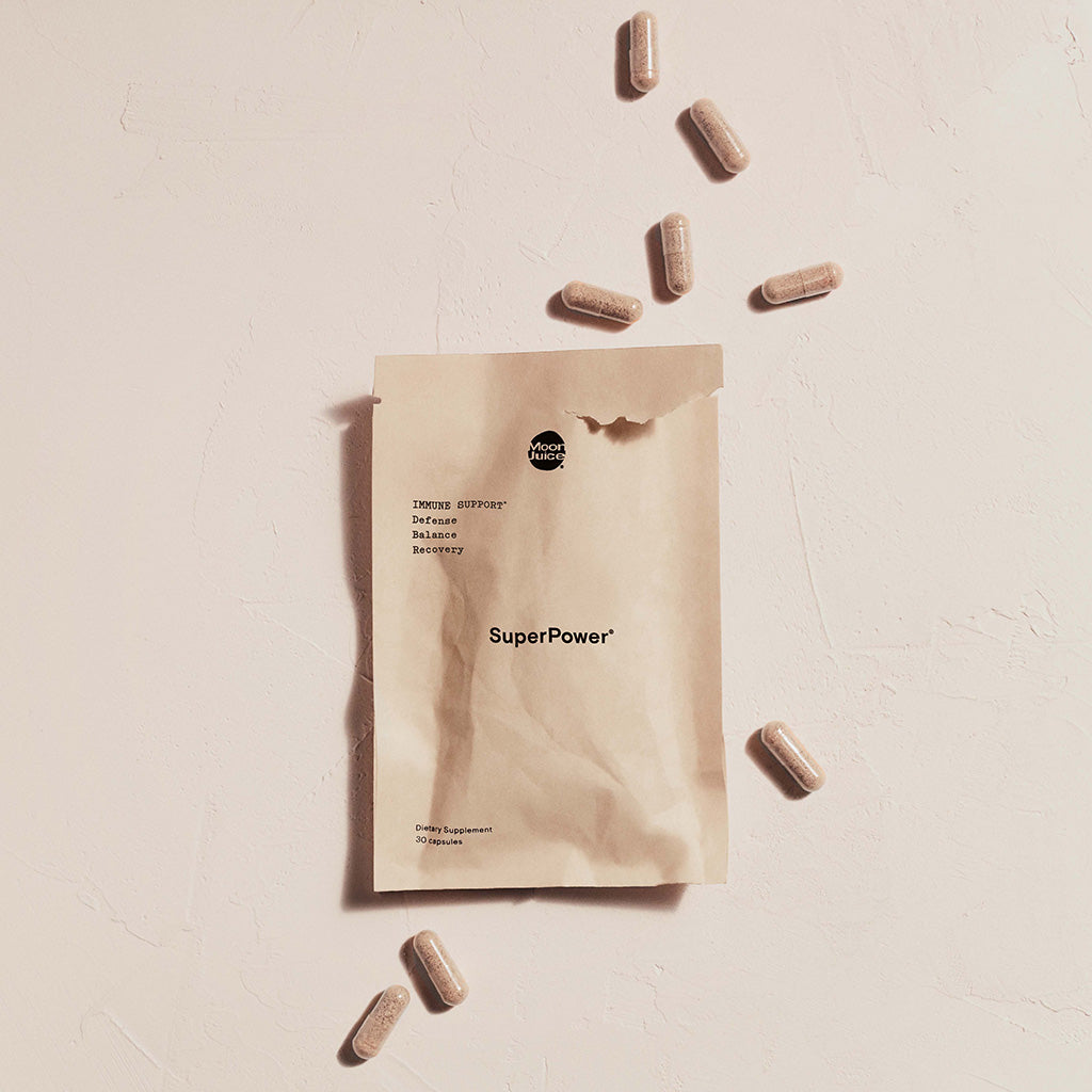 Brown paper supplement pouch labeled 'superpower' with capsules scattered around on a light surface.