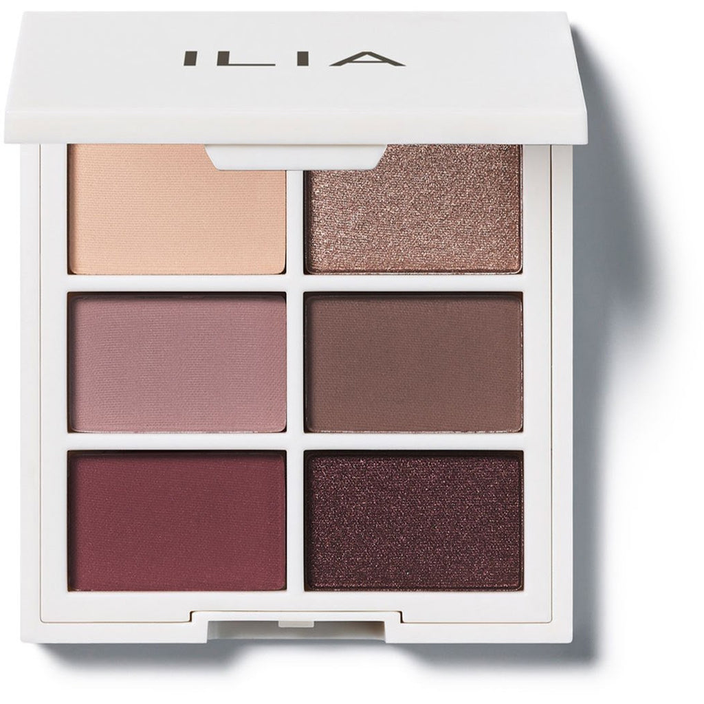 A palette of eyeshadows in neutral and plum tones with matte and shimmer finishes.