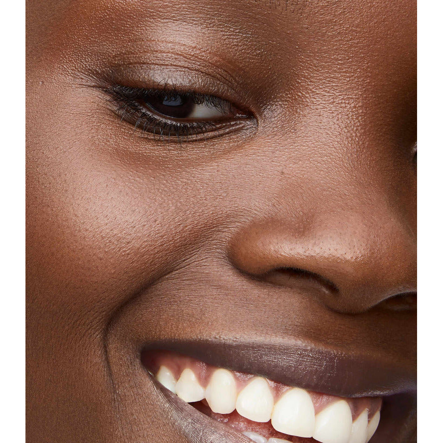 Close-up of a smiling person's face, focusing on the eye and mouth.