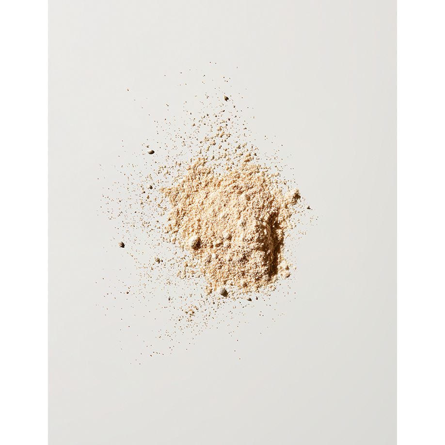 A small pile of finely ground beige powder scattered on a white surface.
