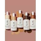 Five bottles of ilia beauty serum arranged in a row against a neutral background.