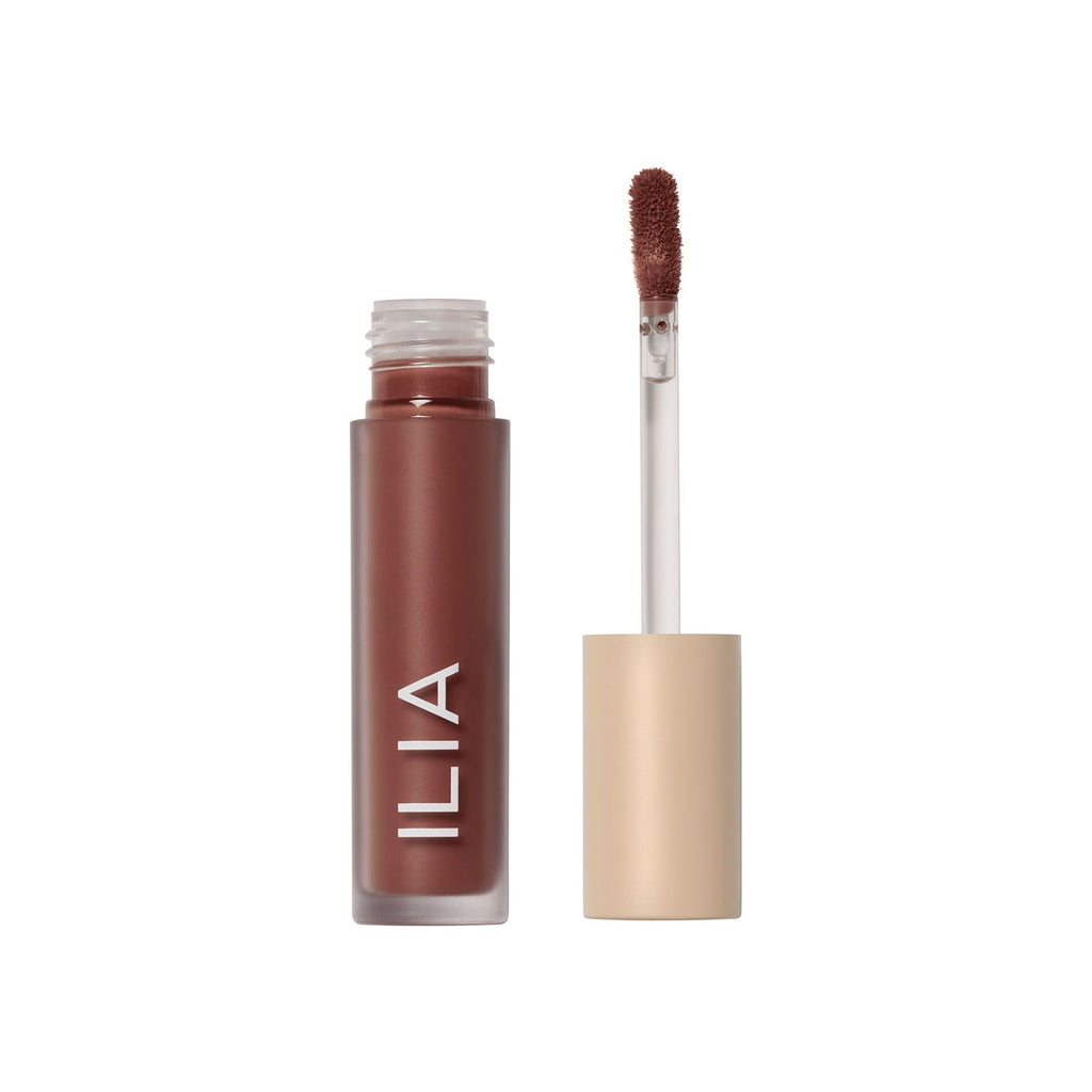 A tube of ilia brand lip gloss with an applicator wand removed, showing the product color.