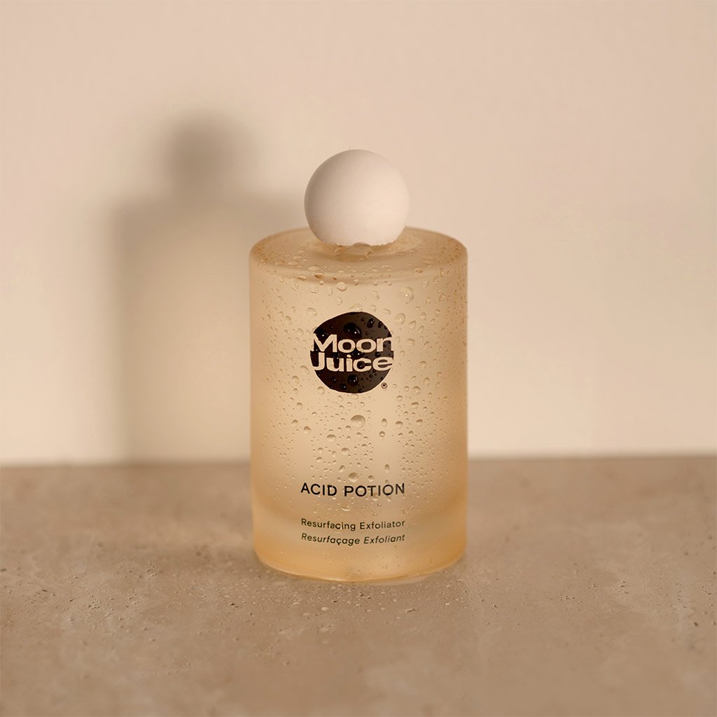 Bottle of moon juice acid potion exfoliator on a neutral background with a spherical cap.
